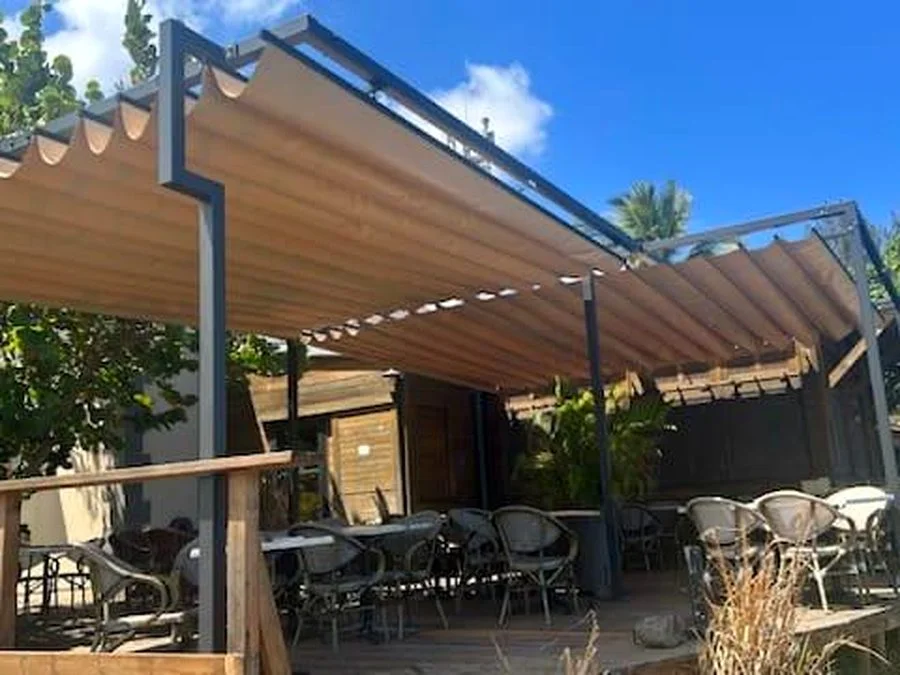 Terrasse de restaurant avec voile d'ombrage rétractable certifiée M1 en bord de mer